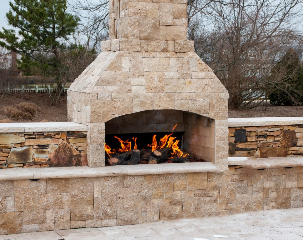 An image of a brick patio fireplace in the backyard of a house