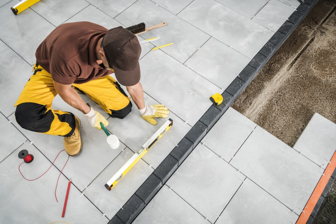 An image of a person working on a concrete paver walkway