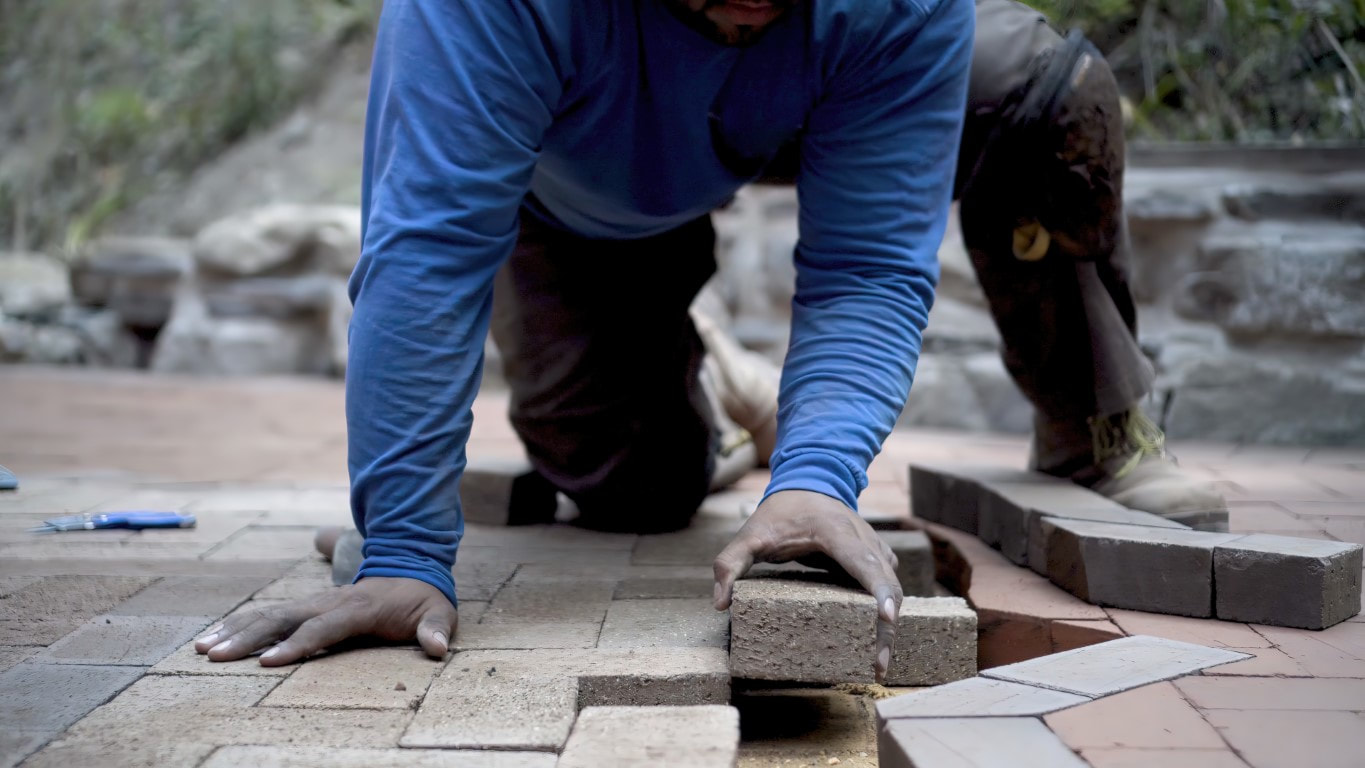 An image of a person applying brick stone in a paver walkway 